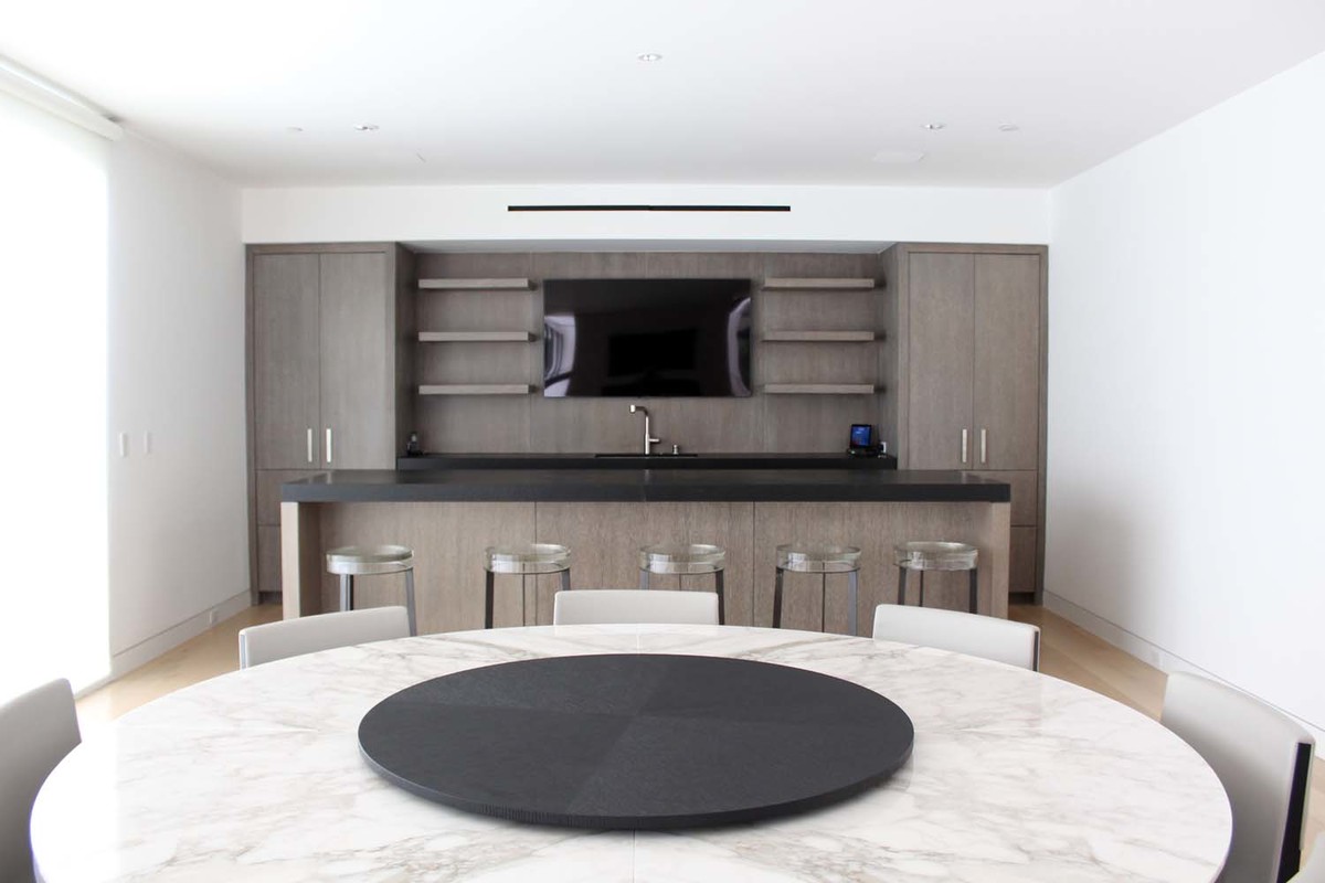 Mid-sized modern u-shaped eat-in kitchen in Los Angeles with a drop-in sink, flat-panel cabinets, grey cabinets, limestone benchtops, stainless steel appliances, light hardwood floors, with island and brown floor.