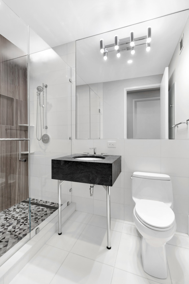Photo of an expansive modern 3/4 bathroom in New York with an open shower, a one-piece toilet, white tile, marble, white walls, porcelain floors, a console sink, marble benchtops, white floor, a hinged shower door, green benchtops, a single vanity, a freestanding vanity and panelled walls.
