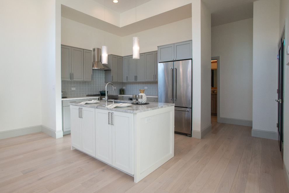 This is an example of a large contemporary l-shaped open plan kitchen in Denver with an undermount sink, shaker cabinets, grey cabinets, granite benchtops, blue splashback, ceramic splashback, stainless steel appliances, medium hardwood floors, with island and white benchtop.