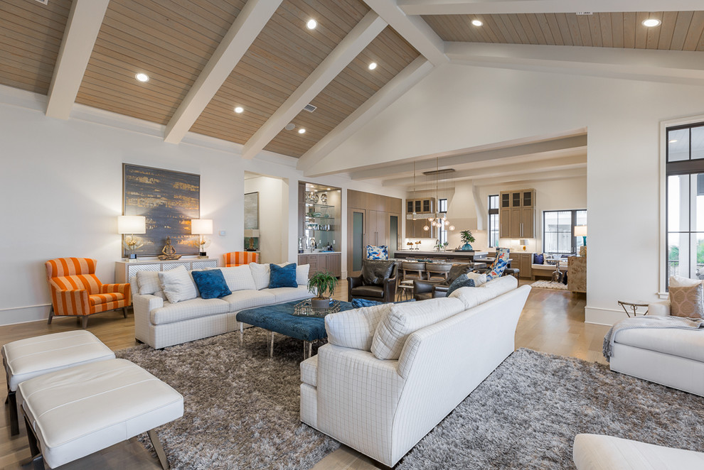 This is an example of a large beach style formal open concept living room in Miami with white walls, light hardwood floors and a wall-mounted tv.