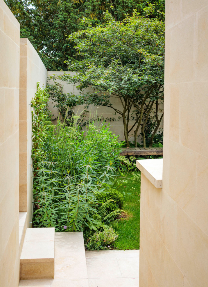 Mittelgroßer, Halbschattiger Moderner Garten im Sommer, hinter dem Haus mit Blumenbeet, Natursteinplatten und Steinzaun in London