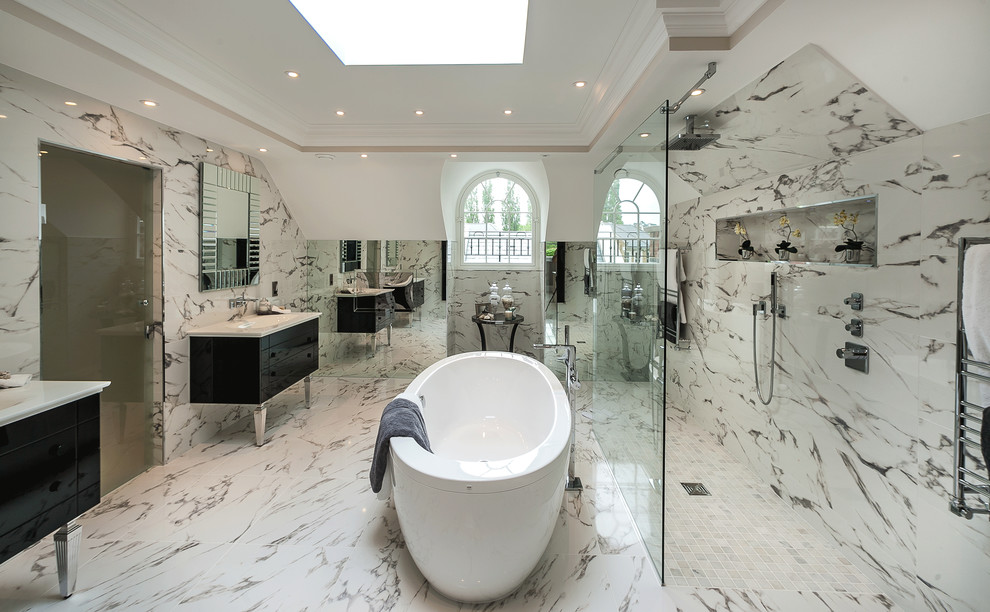 This is an example of a contemporary bathroom in London with an undermount sink, black cabinets, a freestanding tub, an open shower, beige tile, an open shower, marble and flat-panel cabinets.