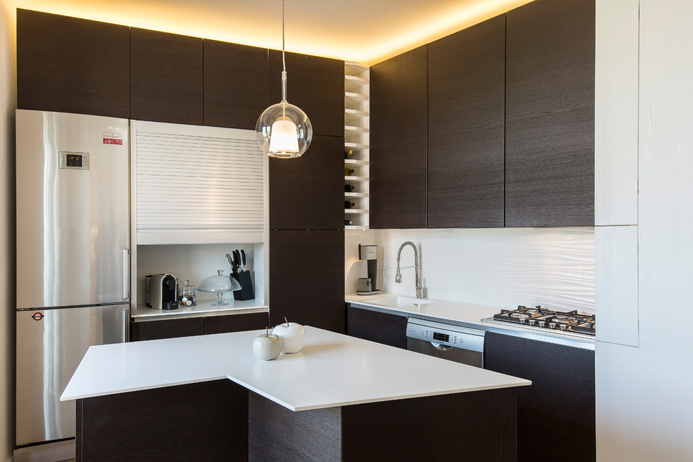 Small contemporary l-shaped open plan kitchen in Milan with an integrated sink, beaded inset cabinets, dark wood cabinets, stainless steel appliances, with island, brown floor, light hardwood floors and white benchtop.