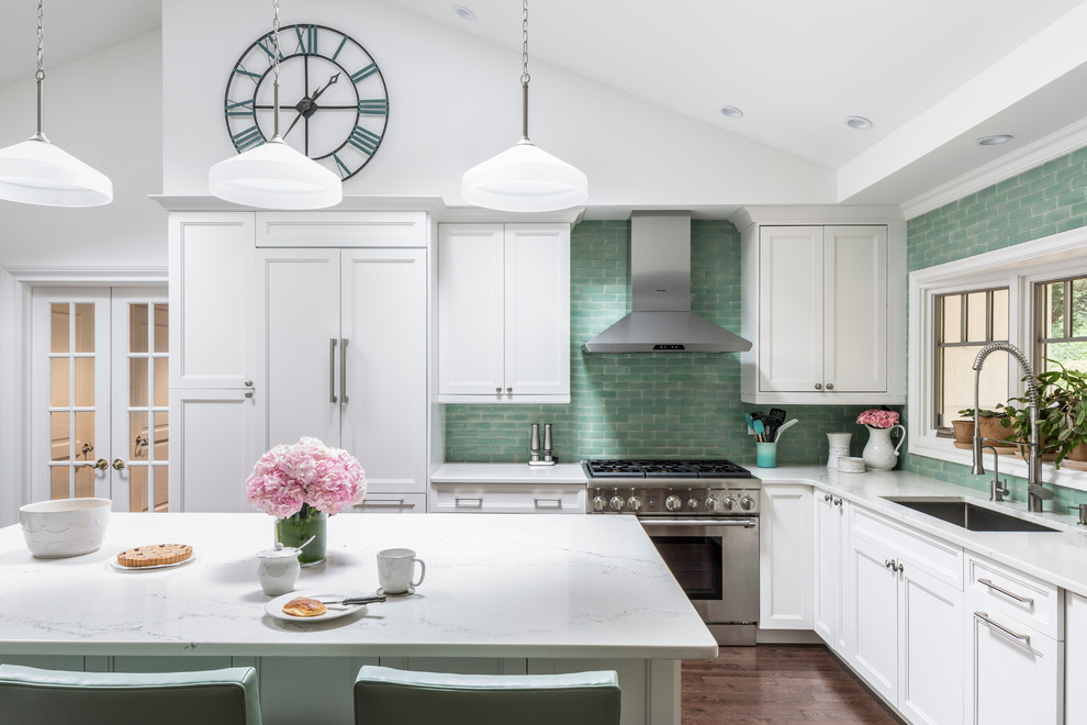 Large transitional l-shaped kitchen in New York with an undermount sink, recessed-panel cabinets, white cabinets, stainless steel benchtops, green splashback, subway tile splashback, stainless steel appliances, dark hardwood floors and with island.