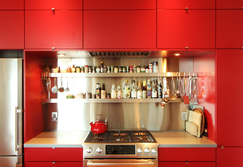 This is an example of a small modern open plan kitchen in Other with an undermount sink, flat-panel cabinets, red cabinets, solid surface benchtops, metal splashback, stainless steel appliances, medium hardwood floors and with island.