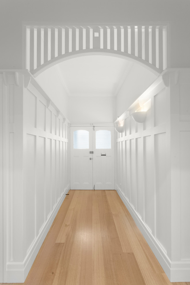 Photo of a mid-sized contemporary hallway in Melbourne with white walls, light hardwood floors, beige floor and decorative wall panelling.