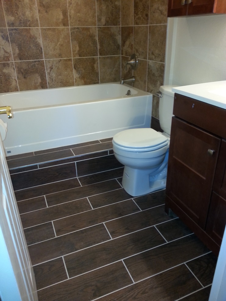 Alcove bathtub - mid-sized transitional 3/4 porcelain tile and brown floor alcove bathtub idea with furniture-like cabinets, dark wood cabinets, a two-piece toilet, white walls, an integrated sink, quartz countertops and white countertops