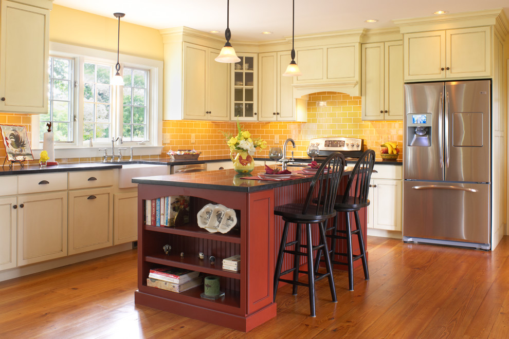 Inspiration for a mid-sized country l-shaped eat-in kitchen in Boston with a farmhouse sink, recessed-panel cabinets, red cabinets, soapstone benchtops, yellow splashback, subway tile splashback, stainless steel appliances, dark hardwood floors and no island.