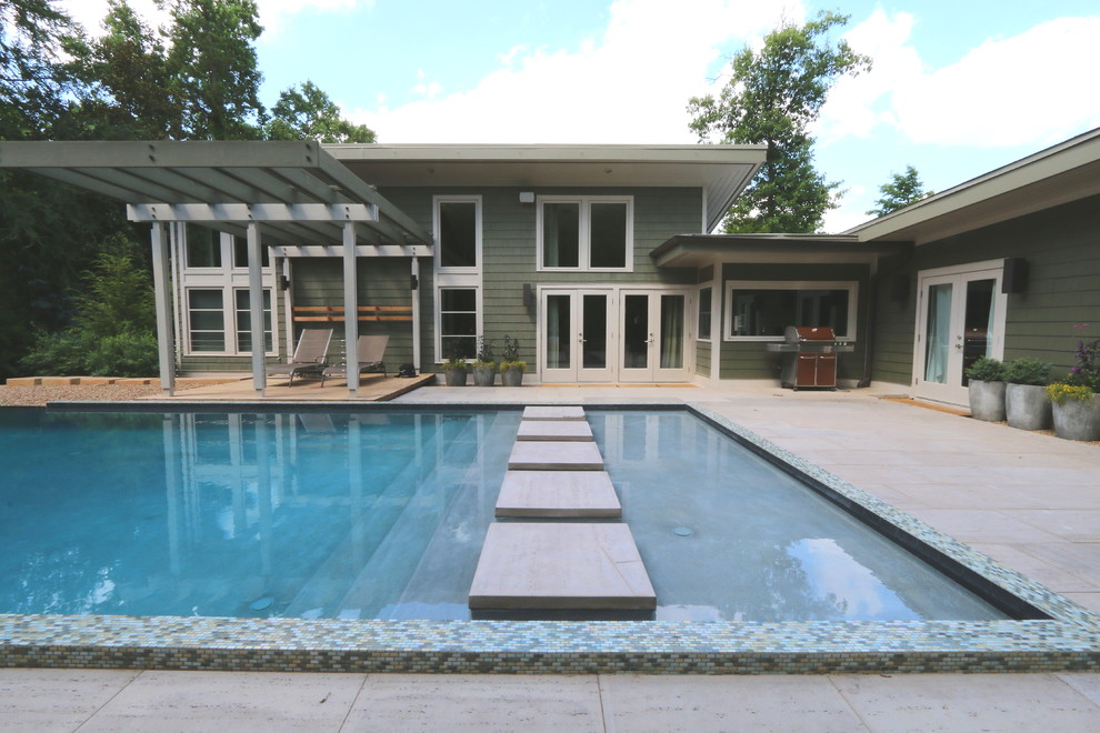 Example of a mid-sized minimalist courtyard concrete paver and rectangular infinity pool fountain design in Raleigh