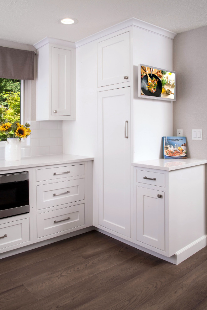 Inspiration for a large transitional l-shaped medium tone wood floor and brown floor open concept kitchen remodel in Seattle with an undermount sink, beaded inset cabinets, white cabinets, quartz countertops, white backsplash, ceramic backsplash, stainless steel appliances, an island and white countertops