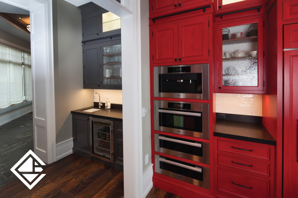 Kitchen - huge rustic l-shaped medium tone wood floor kitchen idea with a farmhouse sink, raised-panel cabinets, red cabinets, granite countertops, white backsplash and stainless steel appliances