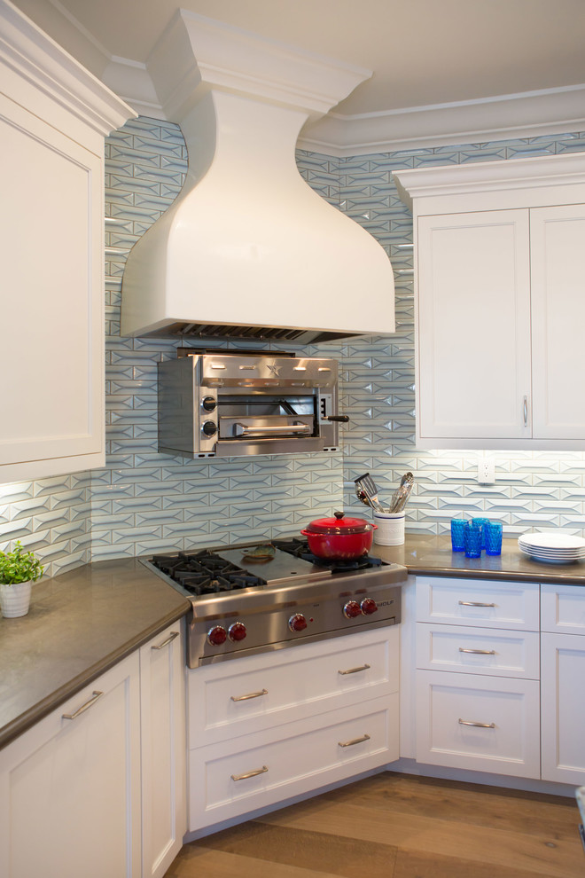 Example of a large transitional u-shaped medium tone wood floor open concept kitchen design in Los Angeles with a farmhouse sink, shaker cabinets, white cabinets, quartz countertops, blue backsplash, ceramic backsplash, stainless steel appliances and an island