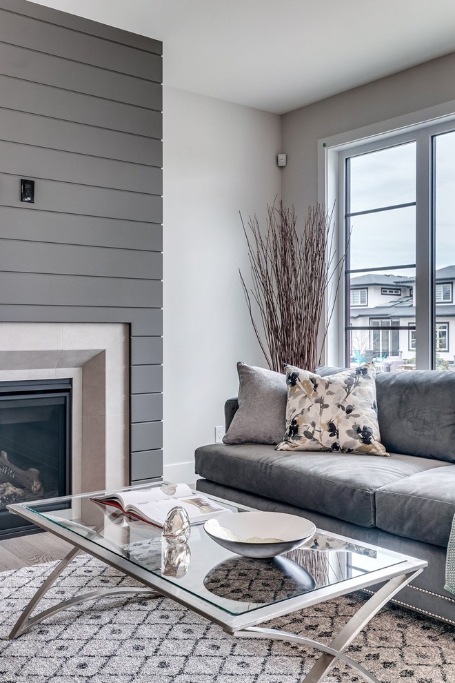 This is an example of a mid-sized modern open concept living room in Calgary with a library, white walls, carpet, a standard fireplace, a wood fireplace surround, a wall-mounted tv and multi-coloured floor.