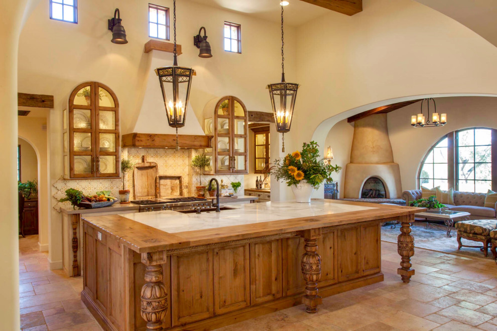 Photo of a large country l-shaped eat-in kitchen in San Diego with a farmhouse sink, glass-front cabinets, distressed cabinets, marble benchtops, beige splashback, terra-cotta splashback, stainless steel appliances, terra-cotta floors, with island, orange floor, beige benchtop and exposed beam.