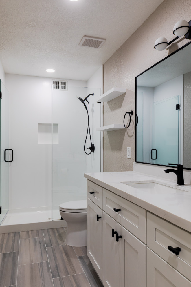 Medium sized midcentury shower room bathroom in San Diego with shaker cabinets, white cabinets, an alcove shower, a one-piece toilet, white walls, ceramic flooring, a submerged sink, engineered stone worktops, brown floors, a hinged door, white worktops, a single sink, a built in vanity unit, brick walls and an alcove bath.