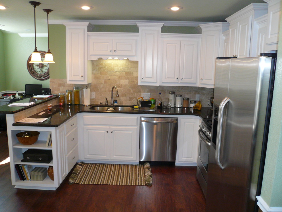 Example of an u-shaped eat-in kitchen design with an undermount sink, raised-panel cabinets, white cabinets, granite countertops, beige backsplash, stone tile backsplash, stainless steel appliances, green walls, engineered wood floors and an island