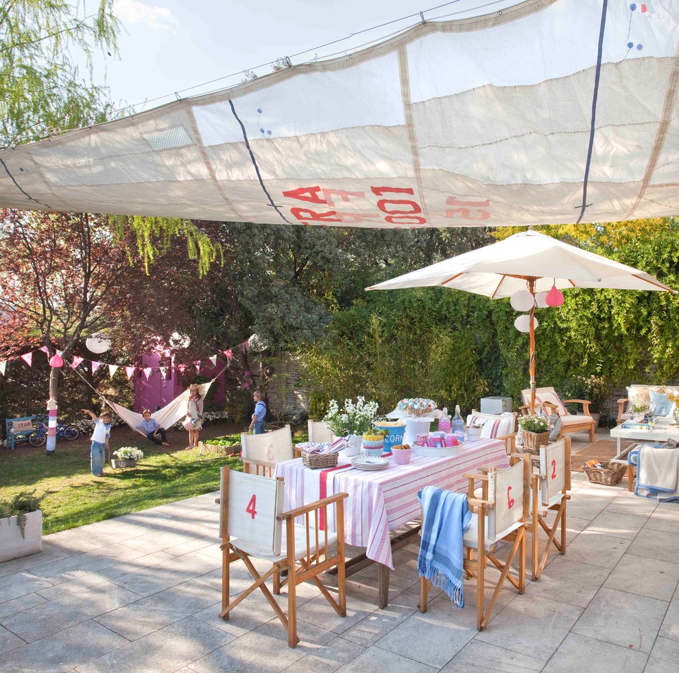 This is an example of a large traditional backyard patio in Madrid with an awning.