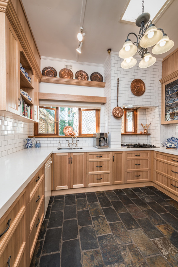 Small traditional u-shaped separate kitchen in Adelaide with an undermount sink, recessed-panel cabinets, light wood cabinets, solid surface benchtops, white splashback, subway tile splashback, slate floors, no island and white appliances.