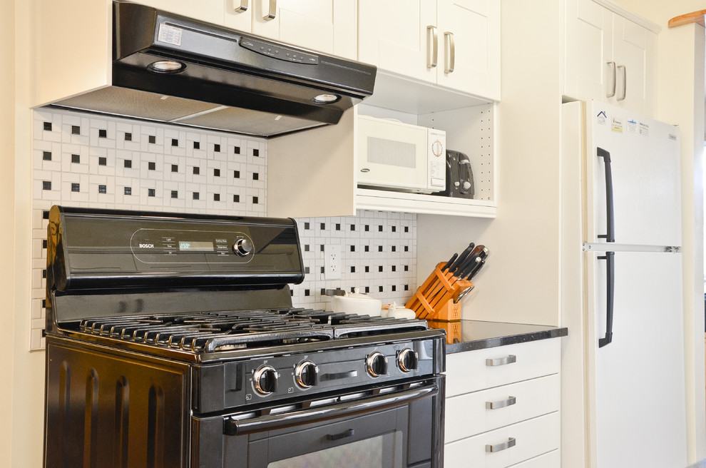 Small transitional galley cork floor kitchen photo in Ottawa with an undermount sink, shaker cabinets, white cabinets, quartz countertops, white backsplash, porcelain backsplash and black appliances