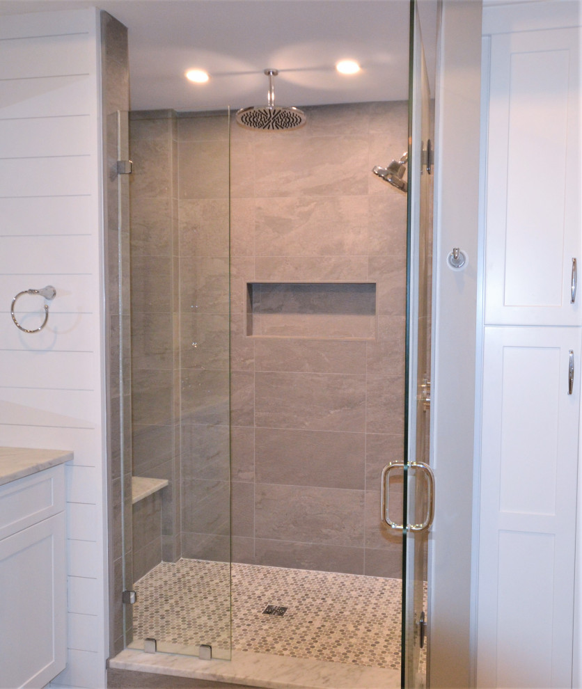 This is an example of a large transitional master bathroom in Philadelphia with shaker cabinets, white cabinets, a corner shower, a one-piece toilet, beige tile, ceramic tile, beige walls, vinyl floors, an undermount sink, engineered quartz benchtops, brown floor, a hinged shower door, beige benchtops, an enclosed toilet, a double vanity, a built-in vanity and planked wall panelling.