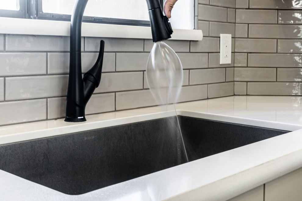 Example of a large transitional u-shaped vinyl floor and gray floor eat-in kitchen design with an undermount sink, shaker cabinets, gray cabinets, quartzite countertops, green backsplash, subway tile backsplash, stainless steel appliances, an island and white countertops