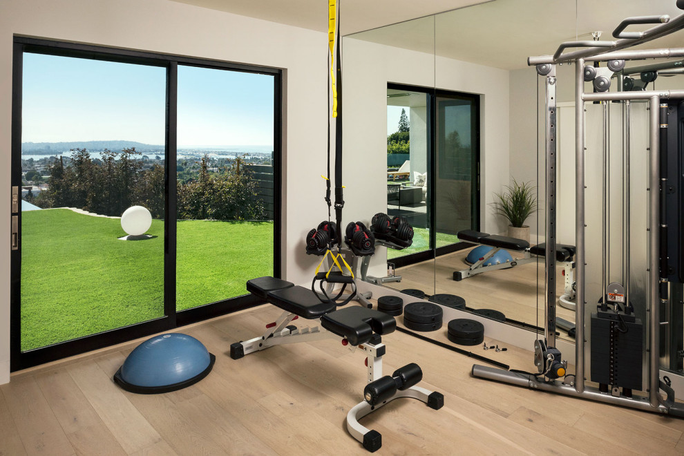 Inspiration for a mid-sized beach style home weight room in San Diego with beige walls, medium hardwood floors and beige floor.