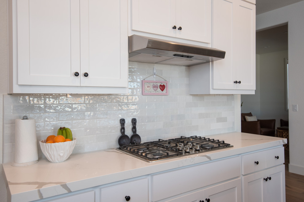 Moderne Wohnküche mit Landhausspüle, Quarzwerkstein-Arbeitsplatte, Küchenrückwand in Weiß, Rückwand aus Keramikfliesen, Kücheninsel und weißer Arbeitsplatte in Sacramento