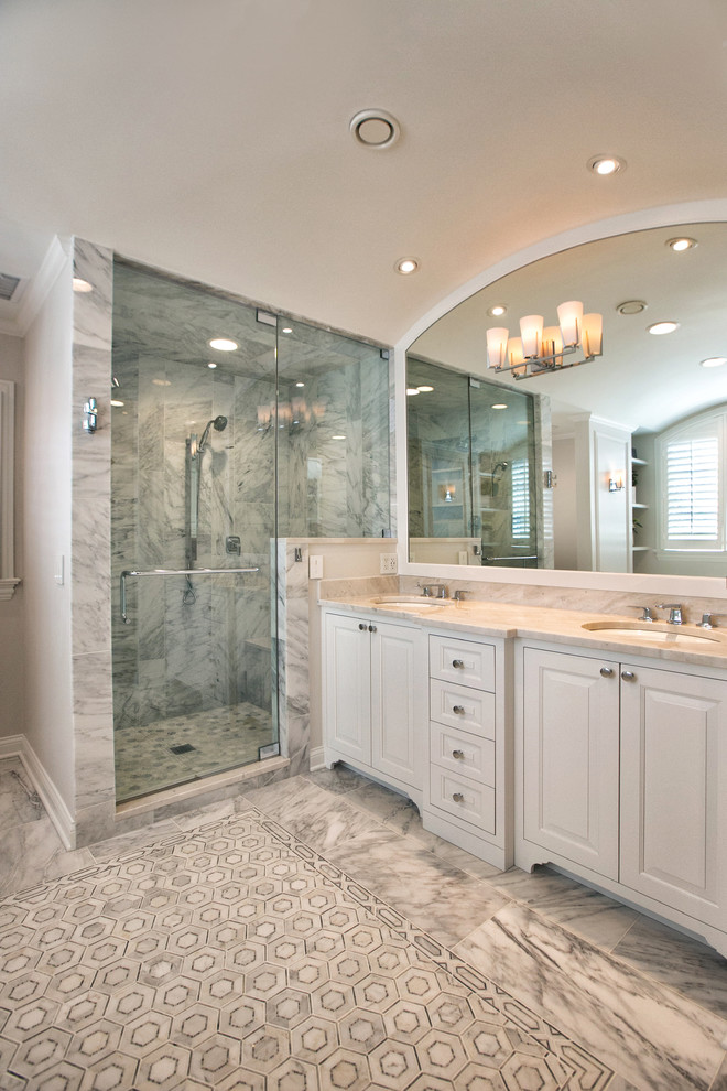 Photo of a mid-sized traditional master wet room bathroom in Chicago with raised-panel cabinets, white cabinets, an undermount tub, a one-piece toilet, white tile, marble, grey walls, marble floors, an undermount sink, marble benchtops, white floor, a hinged shower door and white benchtops.
