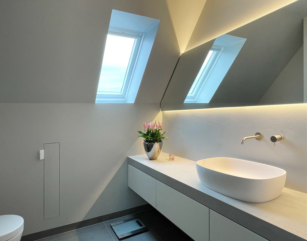Inredning av ett modernt mellanstort grå grått badrum med dusch, med släta luckor, vita skåp, våtrum, en vägghängd toalettstol, grå kakel, grå väggar, klinkergolv i keramik, ett fristående handfat, grått golv och dusch med gångjärnsdörr