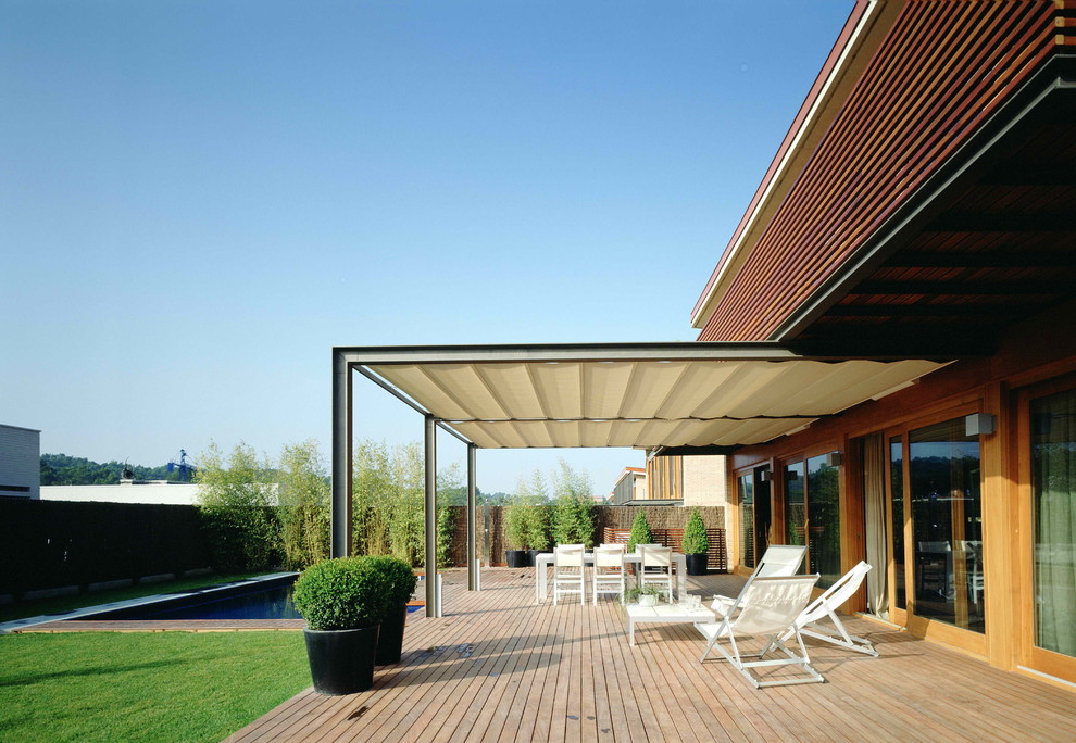 Photo of a large contemporary backyard deck in Barcelona with an awning.