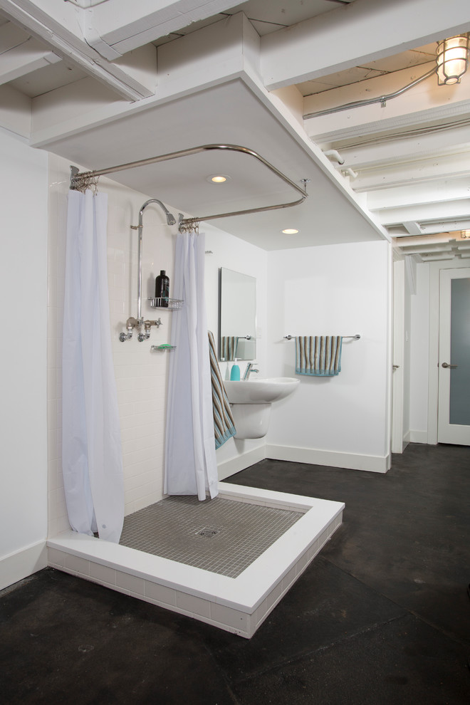 This is an example of a large industrial bathroom in DC Metro with white walls, concrete floors and black floor.