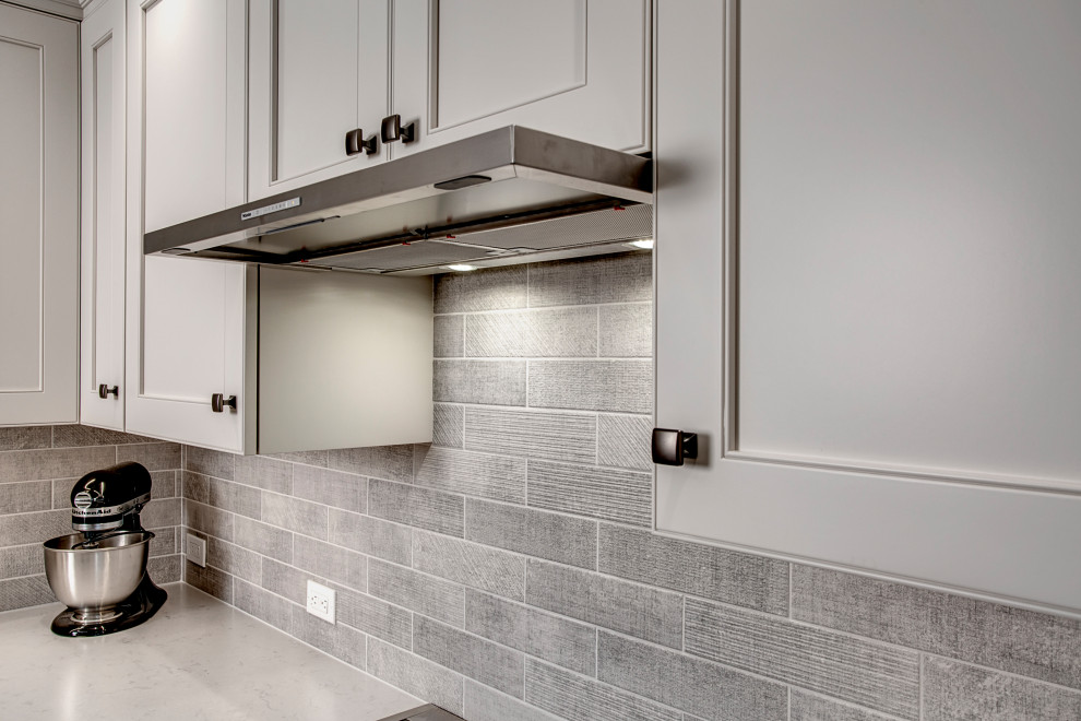 Eat-in kitchen - mid-sized transitional laminate floor and brown floor eat-in kitchen idea in Seattle with a single-bowl sink, shaker cabinets, brown cabinets, quartz countertops, gray backsplash, porcelain backsplash, stainless steel appliances, an island and white countertops