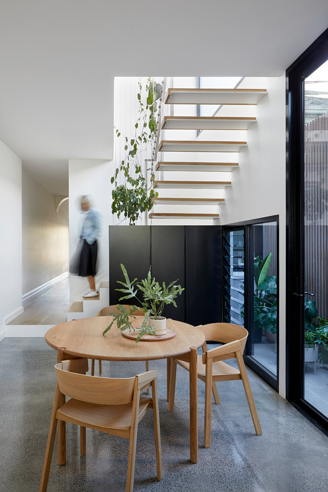 Inspiration for a mid-sized contemporary kitchen/dining combo in Melbourne with white walls, concrete floors and grey floor.