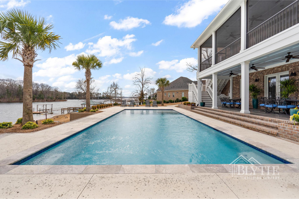 Foto di una grande piscina stile americano rettangolare dietro casa con paesaggistica bordo piscina e lastre di cemento