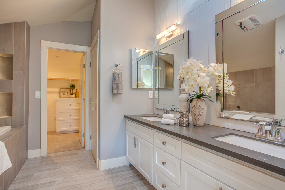 Photo of a country 3/4 bathroom in San Francisco with shaker cabinets, white cabinets, a shower/bathtub combo, a two-piece toilet, beige walls, vinyl floors, an undermount sink, laminate benchtops, a drop-in tub, beige tile and porcelain tile.