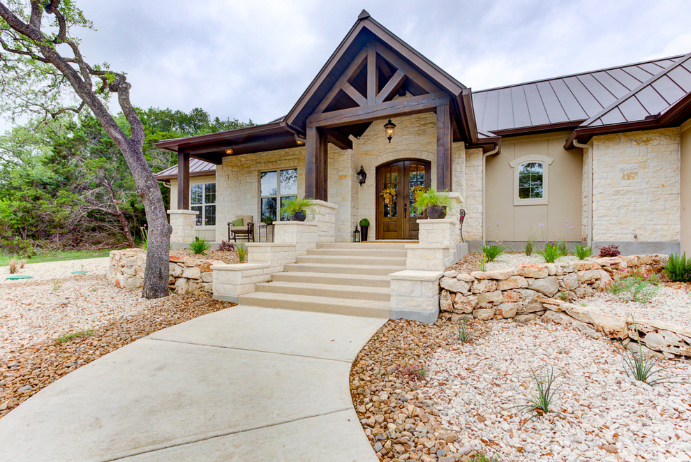 This is an example of a mid-sized country two-storey beige house exterior in Austin with stone veneer, a gable roof and a metal roof.