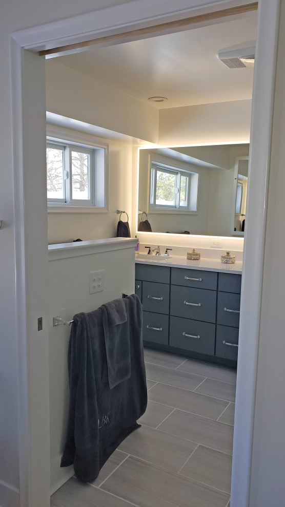 Inspiration for a large transitional master gray tile and porcelain tile porcelain tile, gray floor and double-sink walk-in shower remodel with shaker cabinets, gray cabinets, a two-piece toilet, white walls, an undermount sink, quartz countertops, a hinged shower door, white countertops, a niche and a built-in vanity