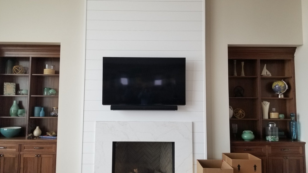 This is an example of a modern living room in Cleveland with a standard fireplace and a wall-mounted tv.