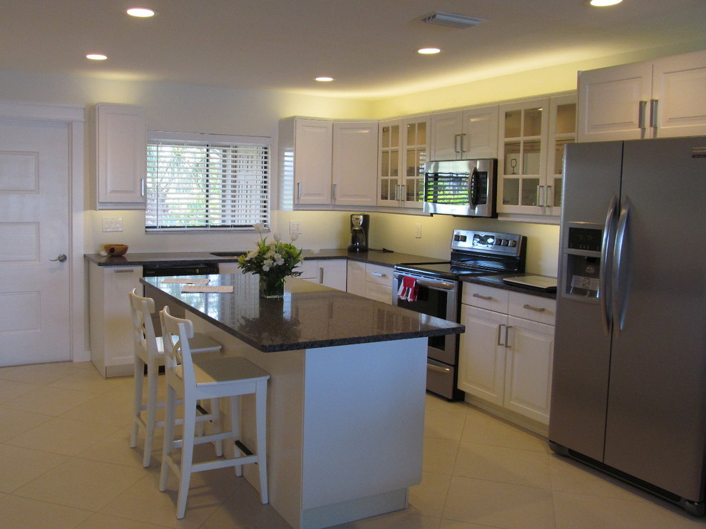 Inspiration for a mid-sized transitional l-shaped travertine floor open concept kitchen remodel in Phoenix with an undermount sink, raised-panel cabinets, white cabinets, granite countertops, white backsplash, stainless steel appliances and an island