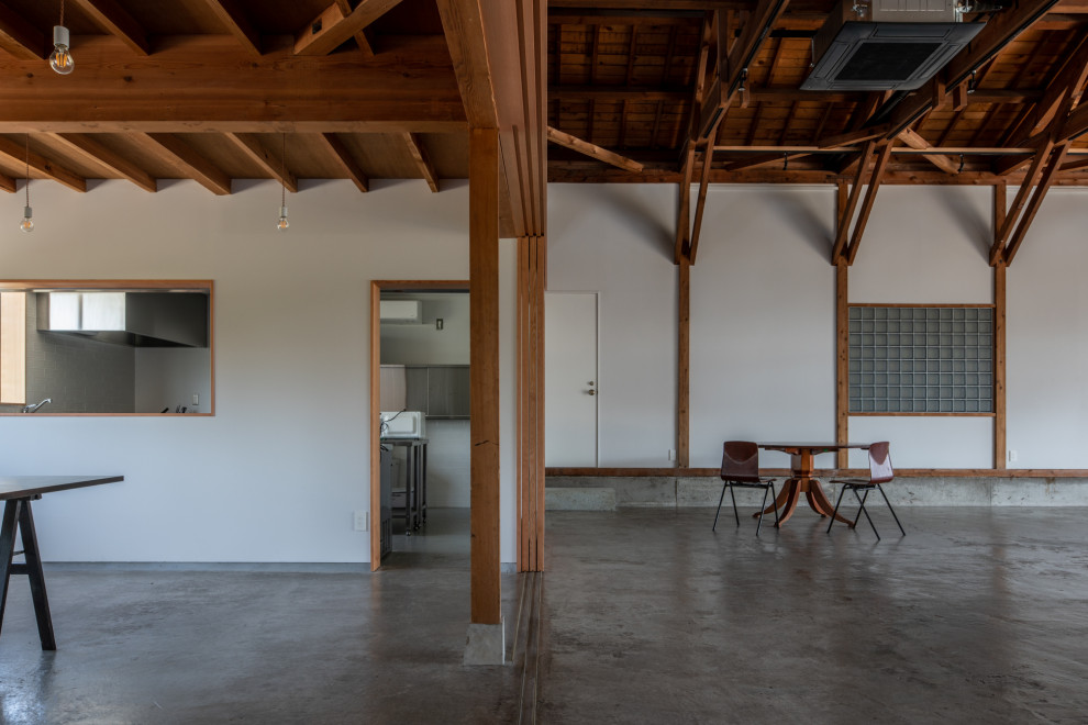 Mittelgroßes Industrial Arbeitszimmer mit Studio, weißer Wandfarbe, Betonboden, grauem Boden und freigelegten Dachbalken in Sonstige