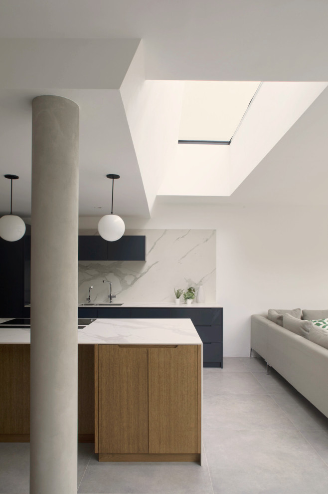 Inspiration for an expansive modern galley open plan kitchen in London with a drop-in sink, flat-panel cabinets, black cabinets, marble benchtops, white splashback, marble splashback, black appliances, porcelain floors, with island, grey floor and white benchtop.