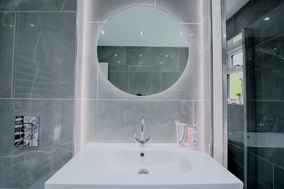 Inspiration for a mid-sized contemporary master wet room bathroom in Manchester with light wood cabinets, a freestanding tub, a wall-mount toilet, gray tile, ceramic tile, grey walls, porcelain floors, a wall-mount sink, grey floor and a hinged shower door.