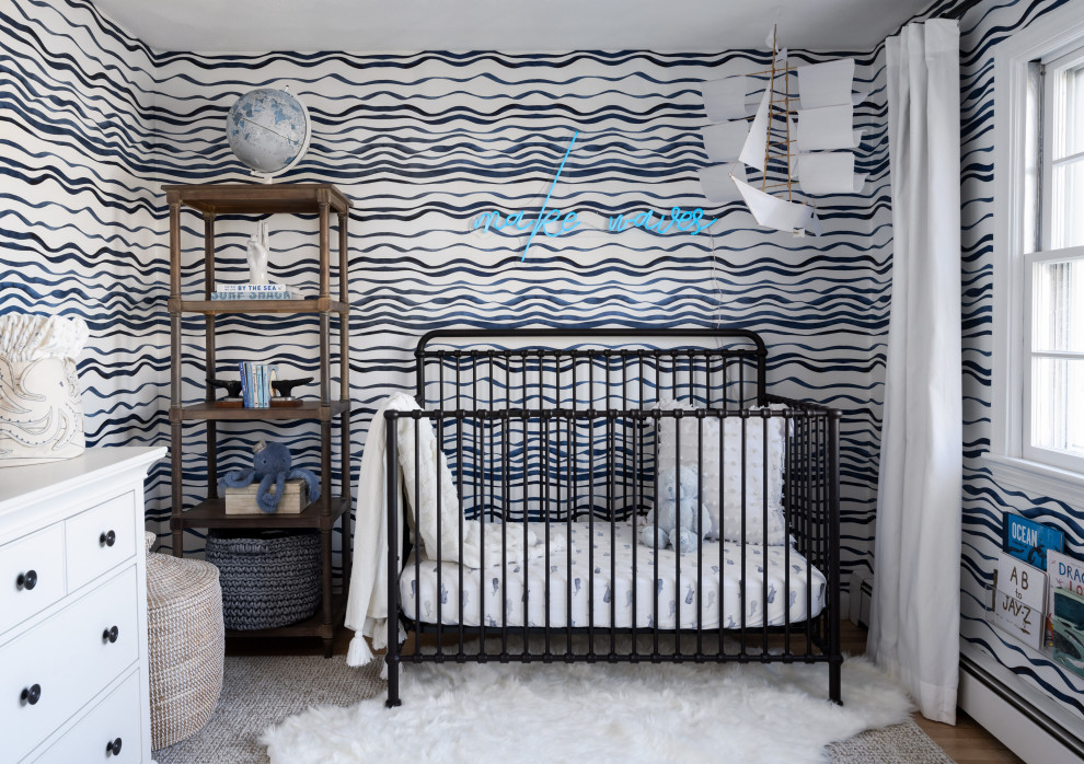 Coastal nursery for boys in Providence with medium hardwood flooring and wallpapered walls.
