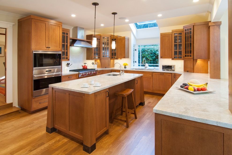 Kitchen - craftsman u-shaped medium tone wood floor kitchen idea in San Francisco with a single-bowl sink, shaker cabinets, medium tone wood cabinets, white backsplash, stainless steel appliances and an island