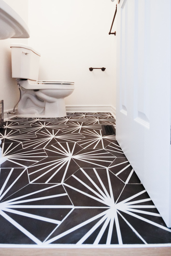 Immagine di un piccolo bagno di servizio nordico con WC monopezzo, pareti bianche, pavimento in gres porcellanato, lavabo a consolle e pavimento nero