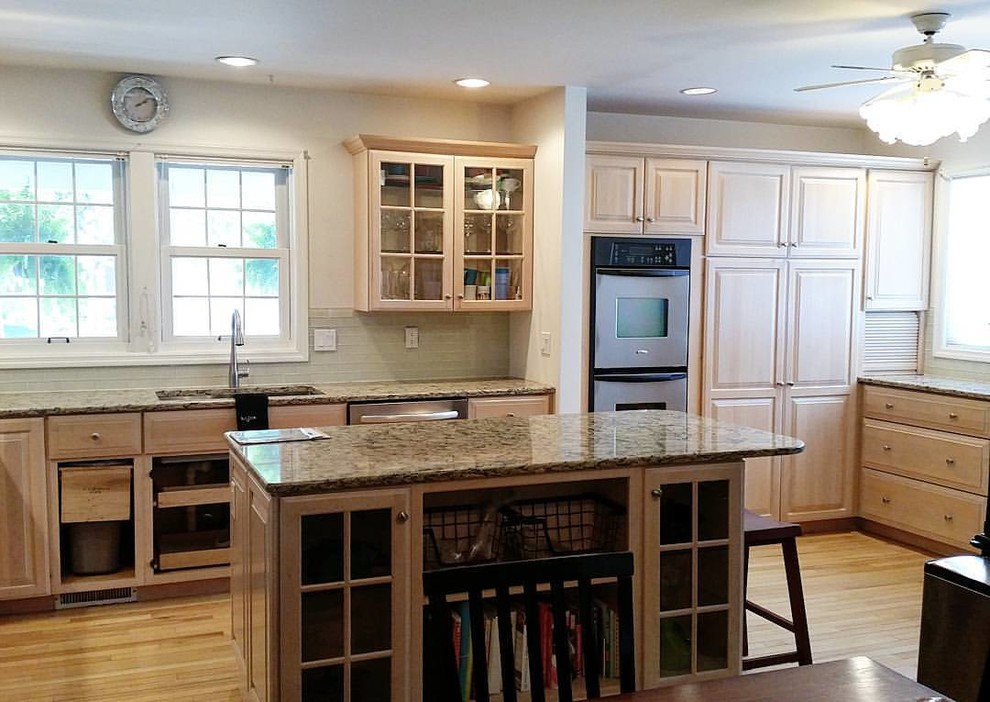 Inspiration for a mid-sized transitional u-shaped medium tone wood floor eat-in kitchen remodel with a double-bowl sink, light wood cabinets, granite countertops, beige backsplash, glass tile backsplash, stainless steel appliances and an island