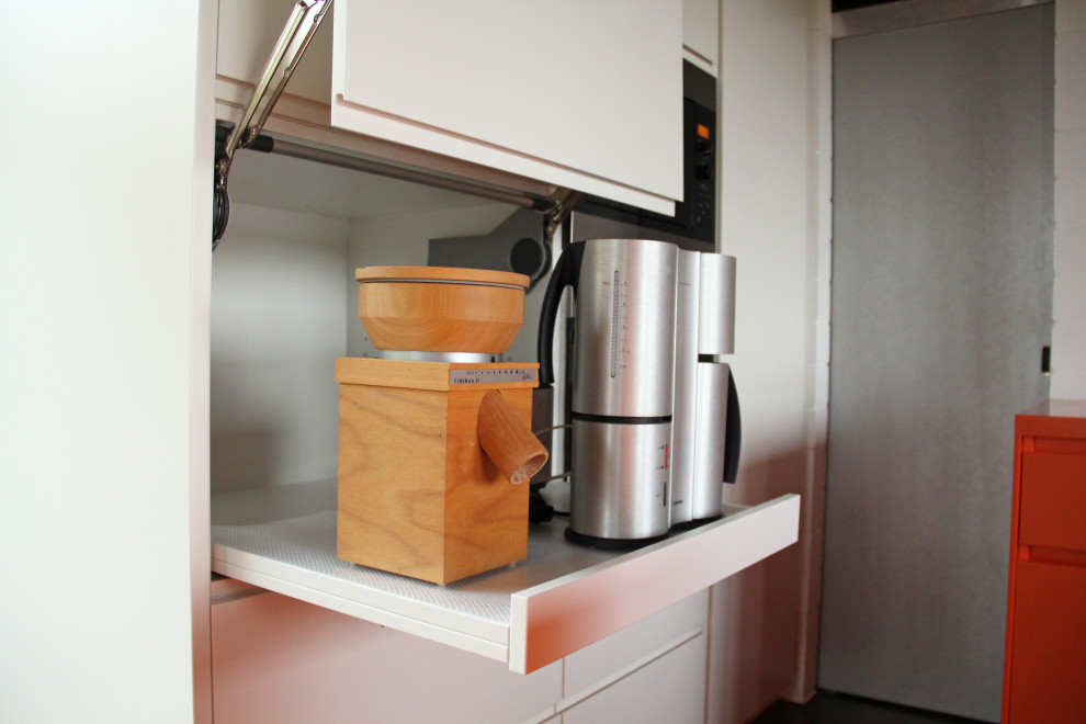 Photo of a mid-sized contemporary u-shaped open plan kitchen in Munich with an undermount sink, flat-panel cabinets, orange cabinets, solid surface benchtops, black appliances, grey floor and orange benchtop.