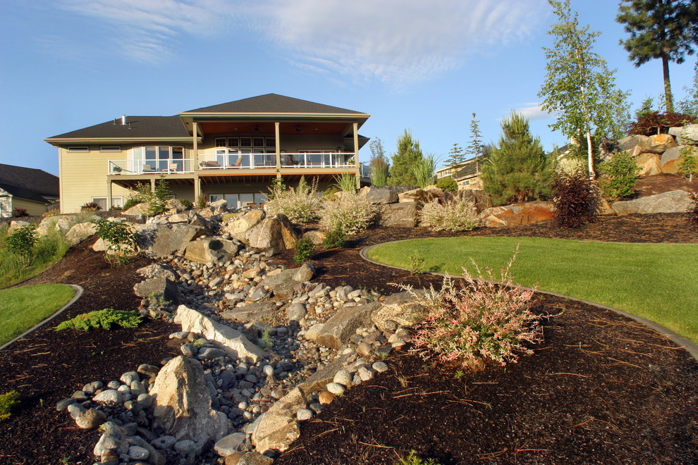 This is an example of a large contemporary backyard formal garden in Seattle with a water feature and natural stone pavers.