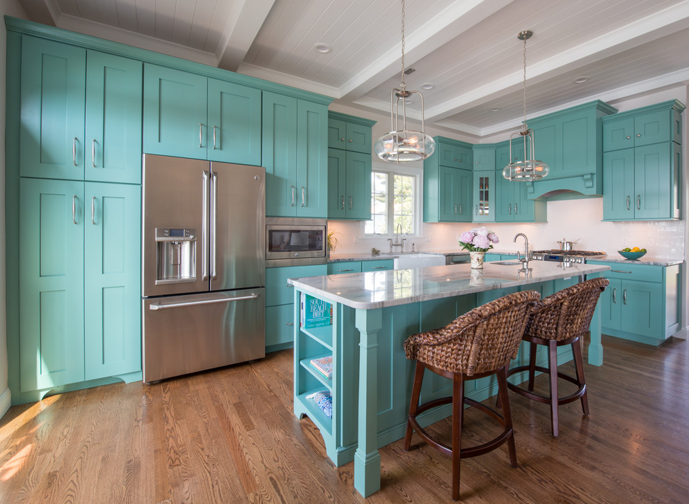 Inspiration for a beach style l-shaped kitchen in Providence with a farmhouse sink, shaker cabinets, turquoise cabinets, white splashback, stainless steel appliances, medium hardwood floors and with island.
