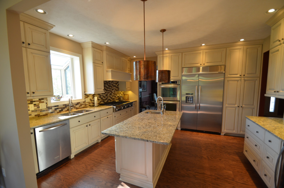 Inspiration for a mid-sized transitional u-shaped medium tone wood floor and brown floor eat-in kitchen remodel with an undermount sink, raised-panel cabinets, beige cabinets, granite countertops, multicolored backsplash, mosaic tile backsplash, stainless steel appliances, an island and multicolored countertops